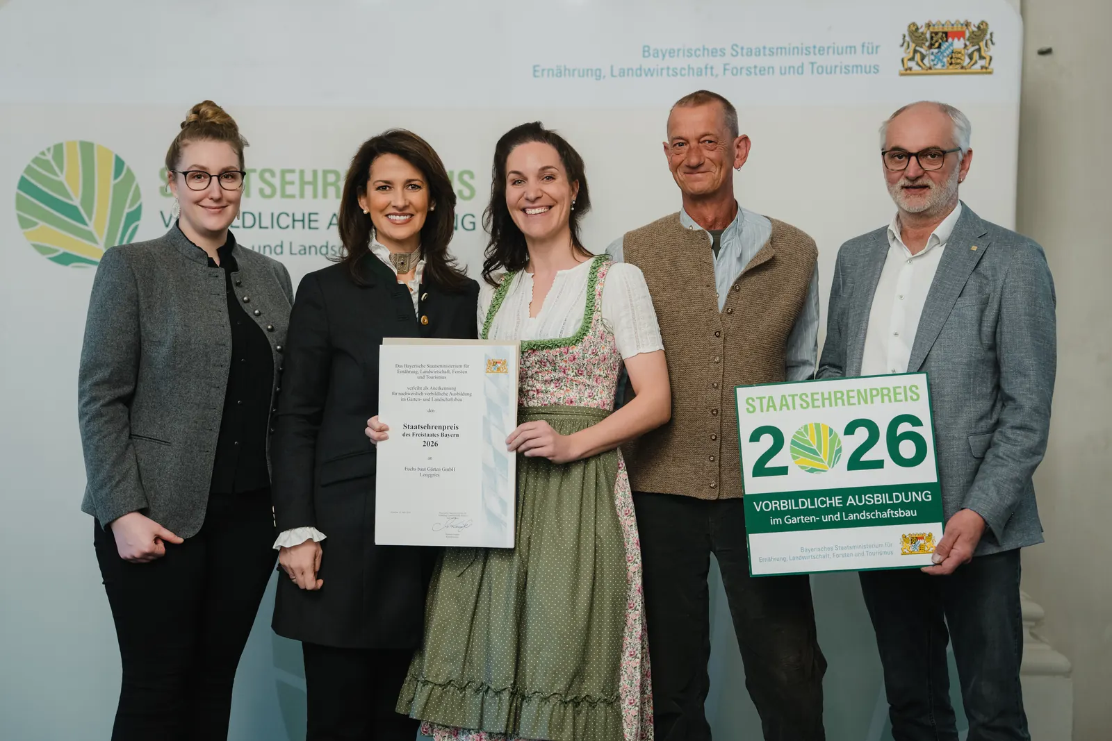 Balbina Fuchs mit den Ausbildern Katharina Freiseisen und Rupprecht von Sigriz bei der Übergabe des Bayerischen Staatsehrenpreises 2026 für vorbildliche Ausbildung im Garten- und Landschaftsbau