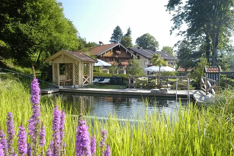 Schwimmteich mit Holzdeck und Badehaus am Landhaus Benediktenhof in Arzbach, gebaut von Fuchs baut Gärten