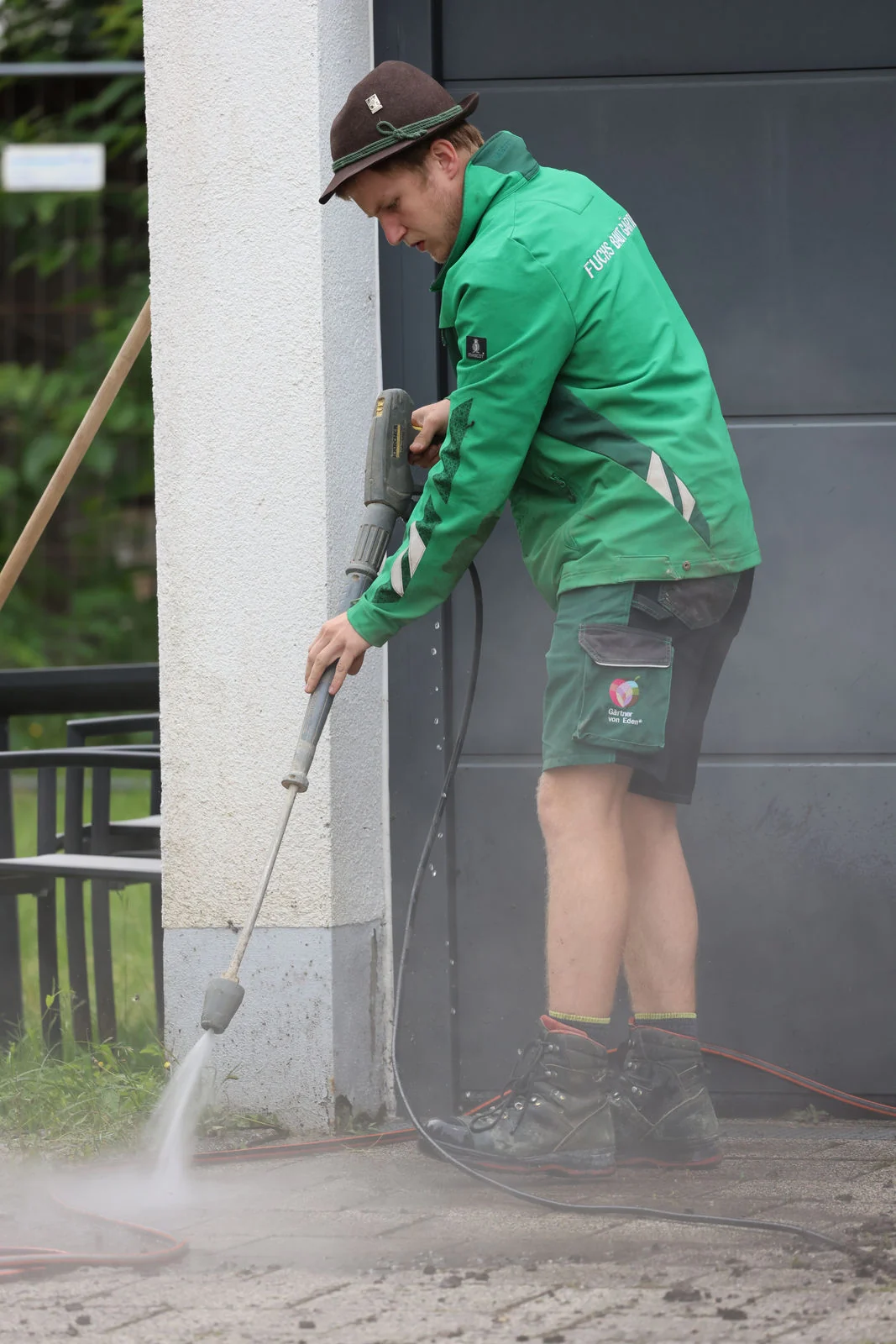 Kollege reinigt eine Sichtbetonmauer mit dem Hochdruckreiniger