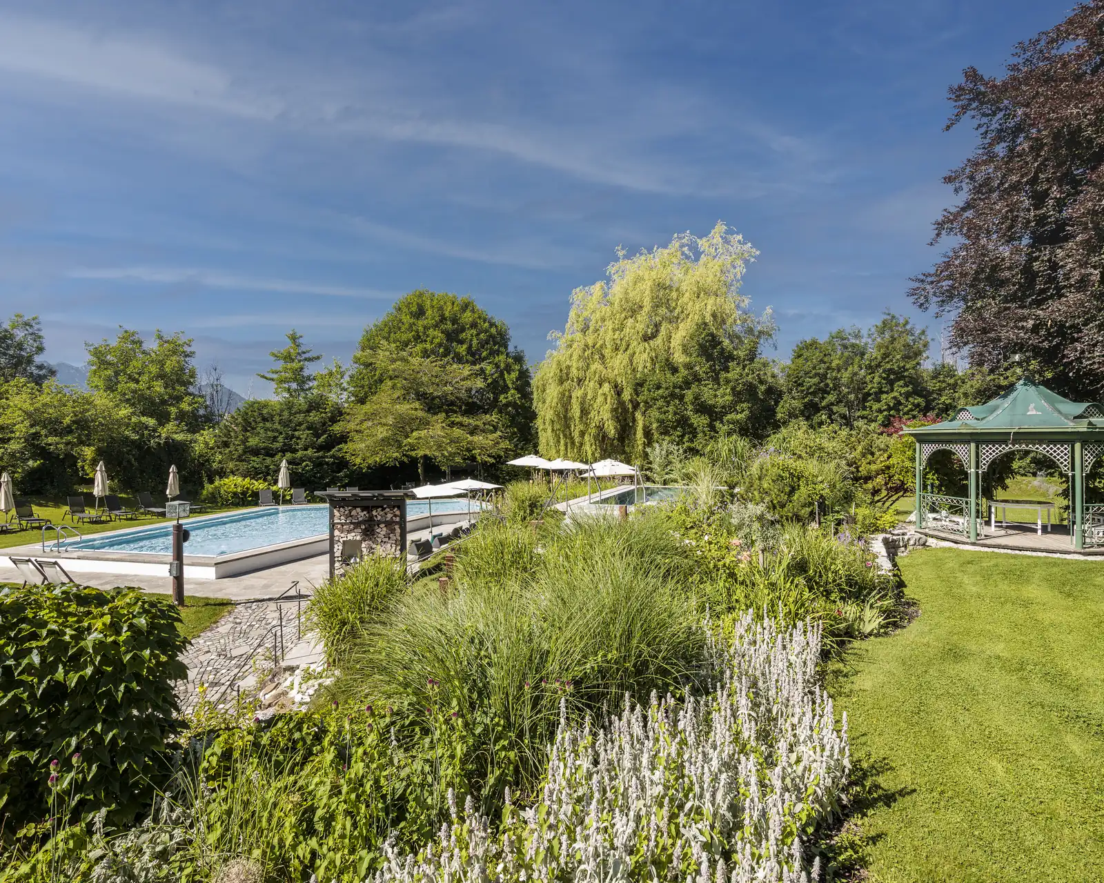 Staudenbeete am Pool des Alpenhof Murnau mit Gräsern und Blick ins Murnauer Moos