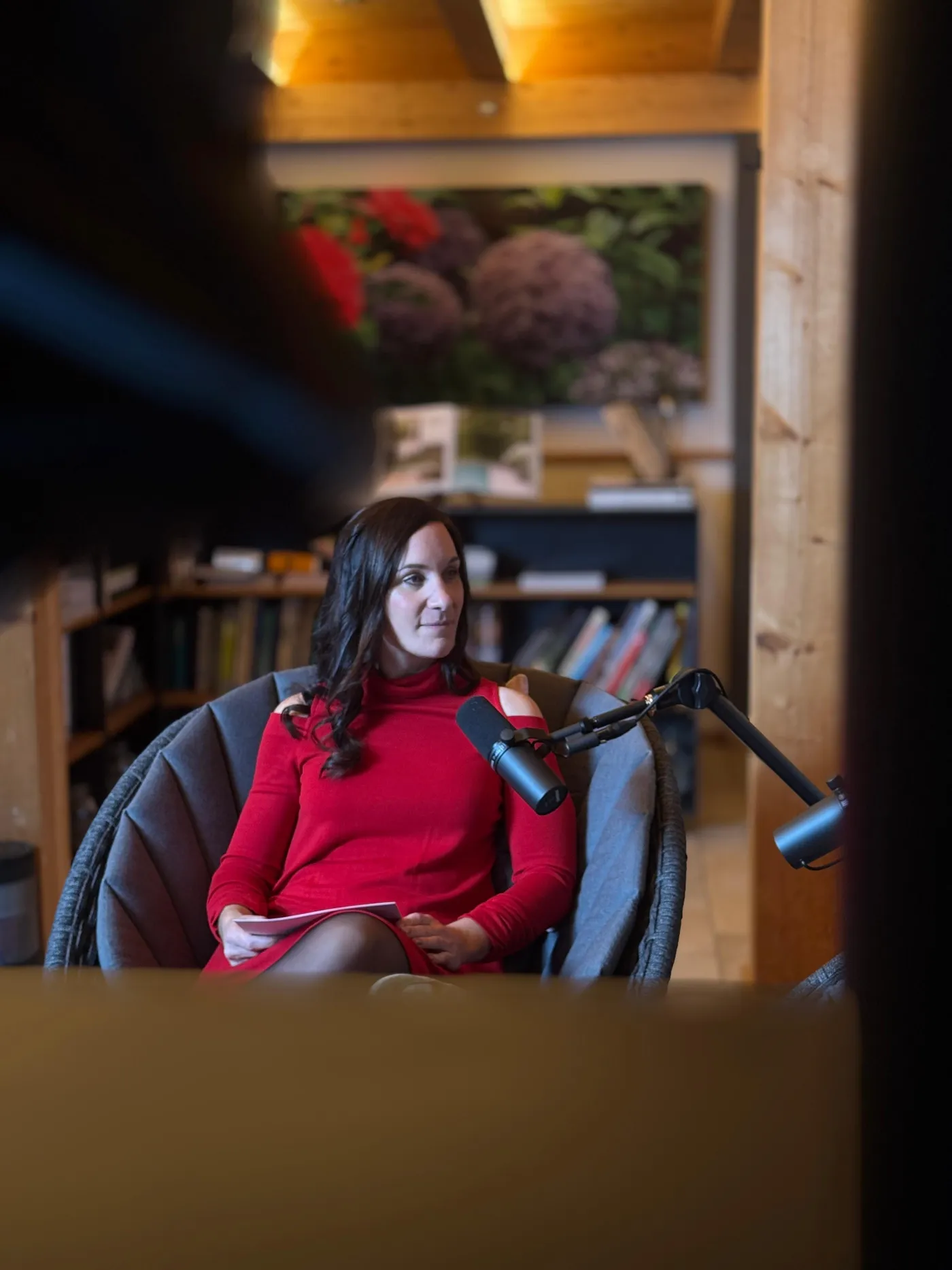 Balbina Fuchs am Mikrofon vor dem Bücherregal während einer Podcast-Aufnahme
