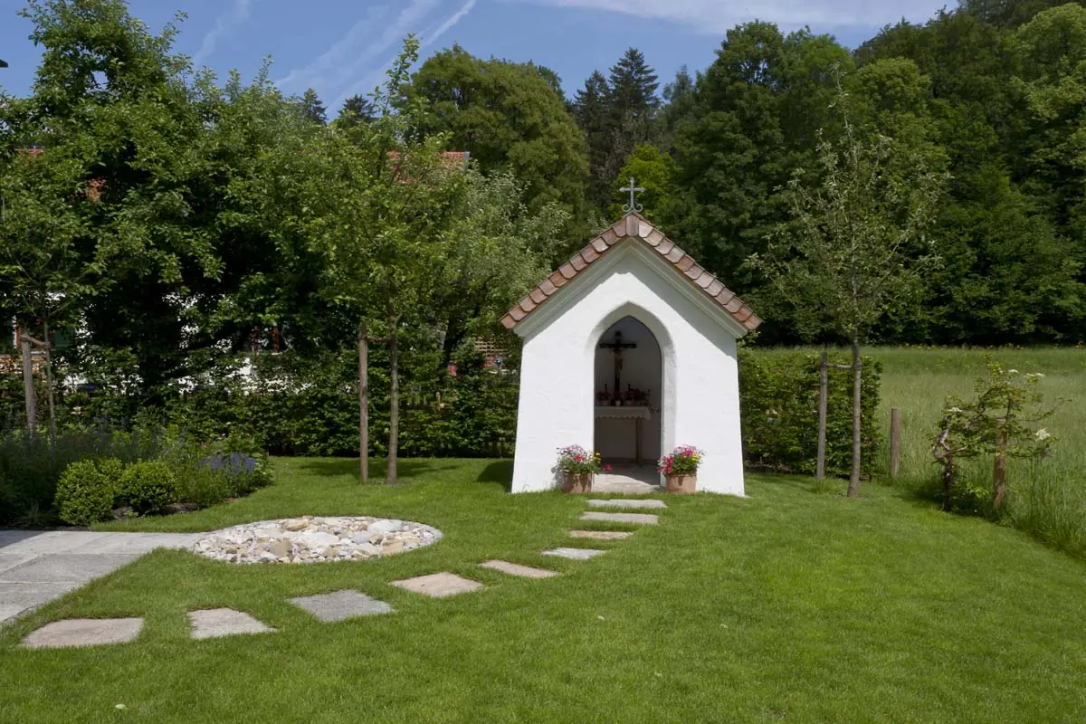 Trittplatten führen über den Rasen zur kleinen Kapelle