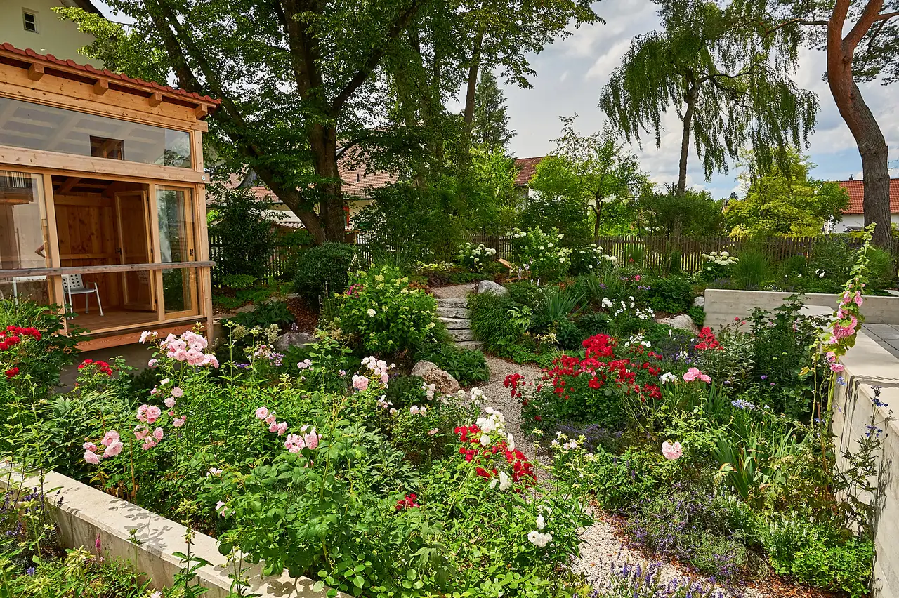 Rosen und Stauden bis an die Wand des Gartenhauses