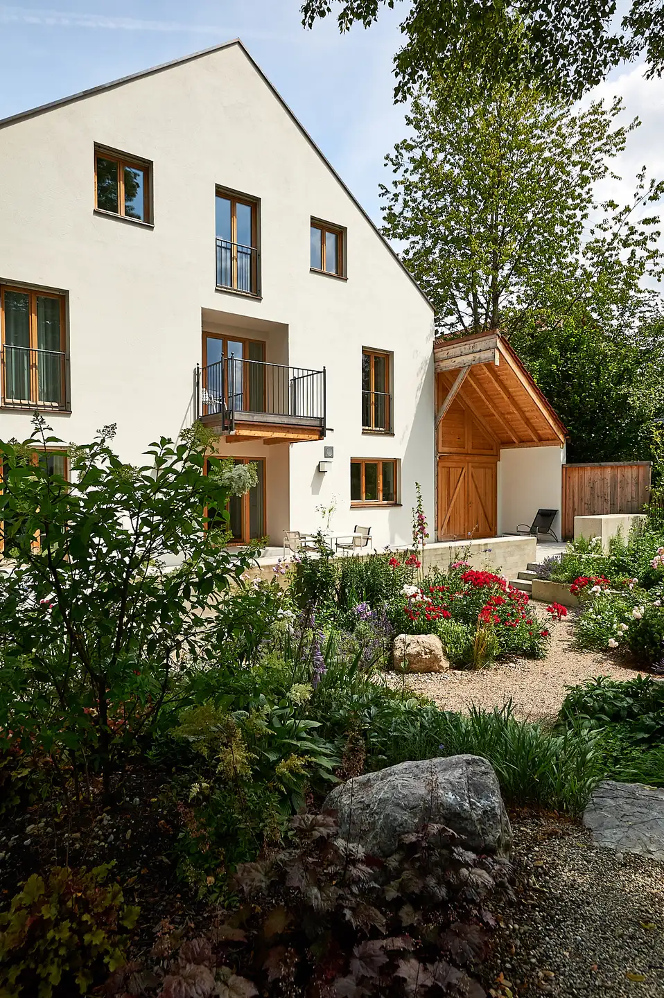Das Haus von der Straßenseite, davor Rosen, Gräser und Findlinge