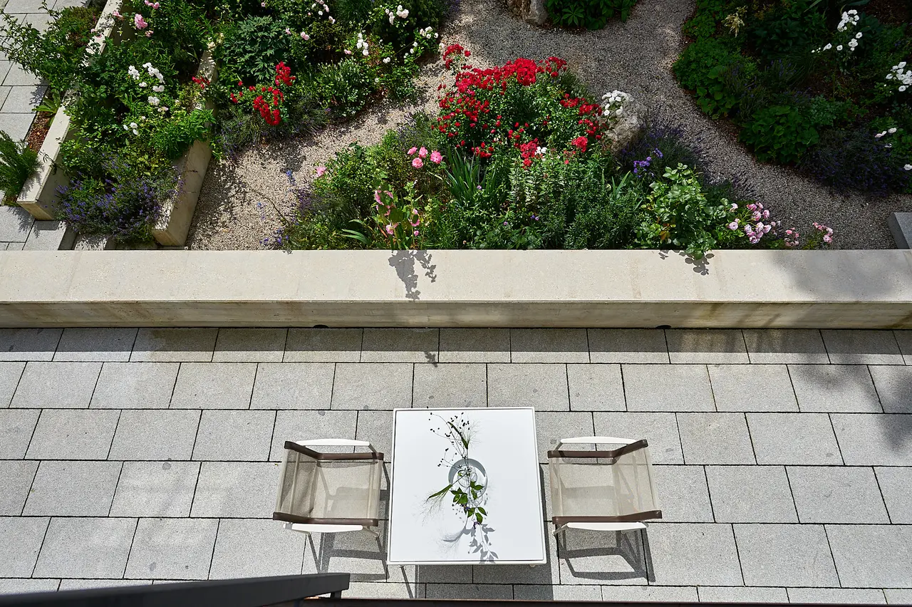 Die Terrasse mit Tisch, davor die Sitzmauer und das Beet