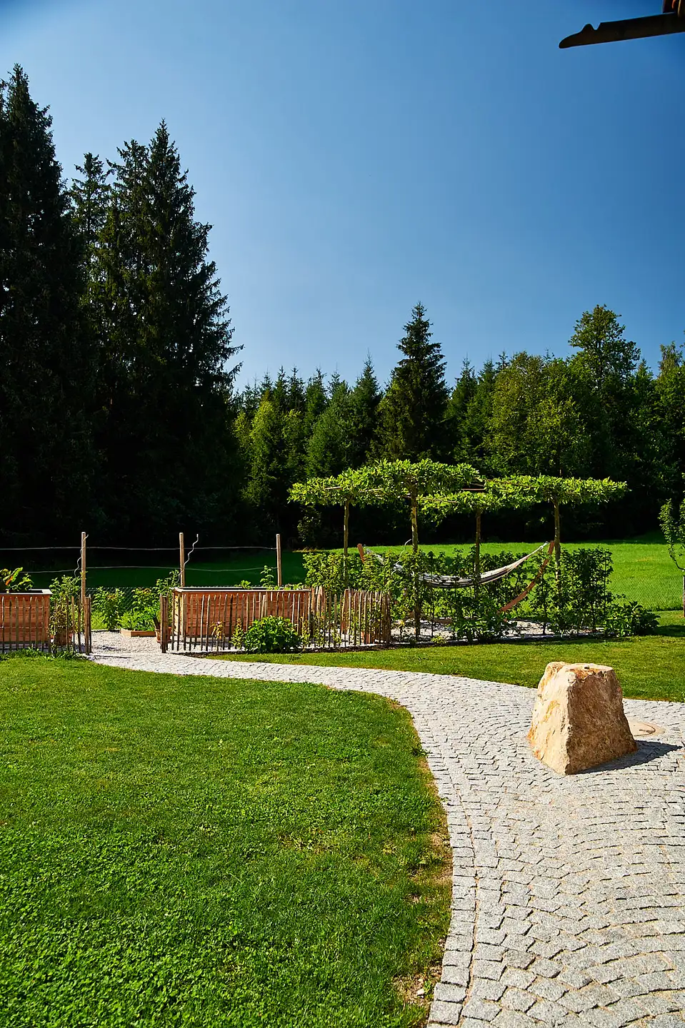 Der Kleinsteinweg mit Findling, dahinter Obstbäume und Waldrand