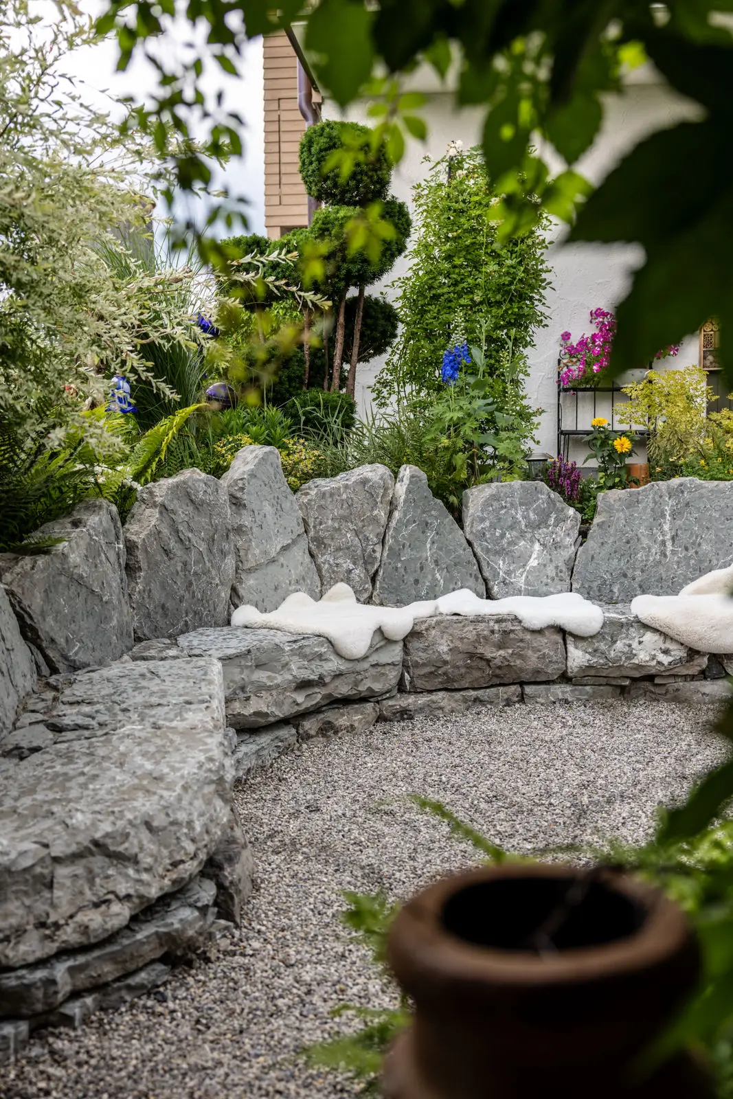 Die geschwungene Mauer des Sitzkreises, davor der Kiesbelag