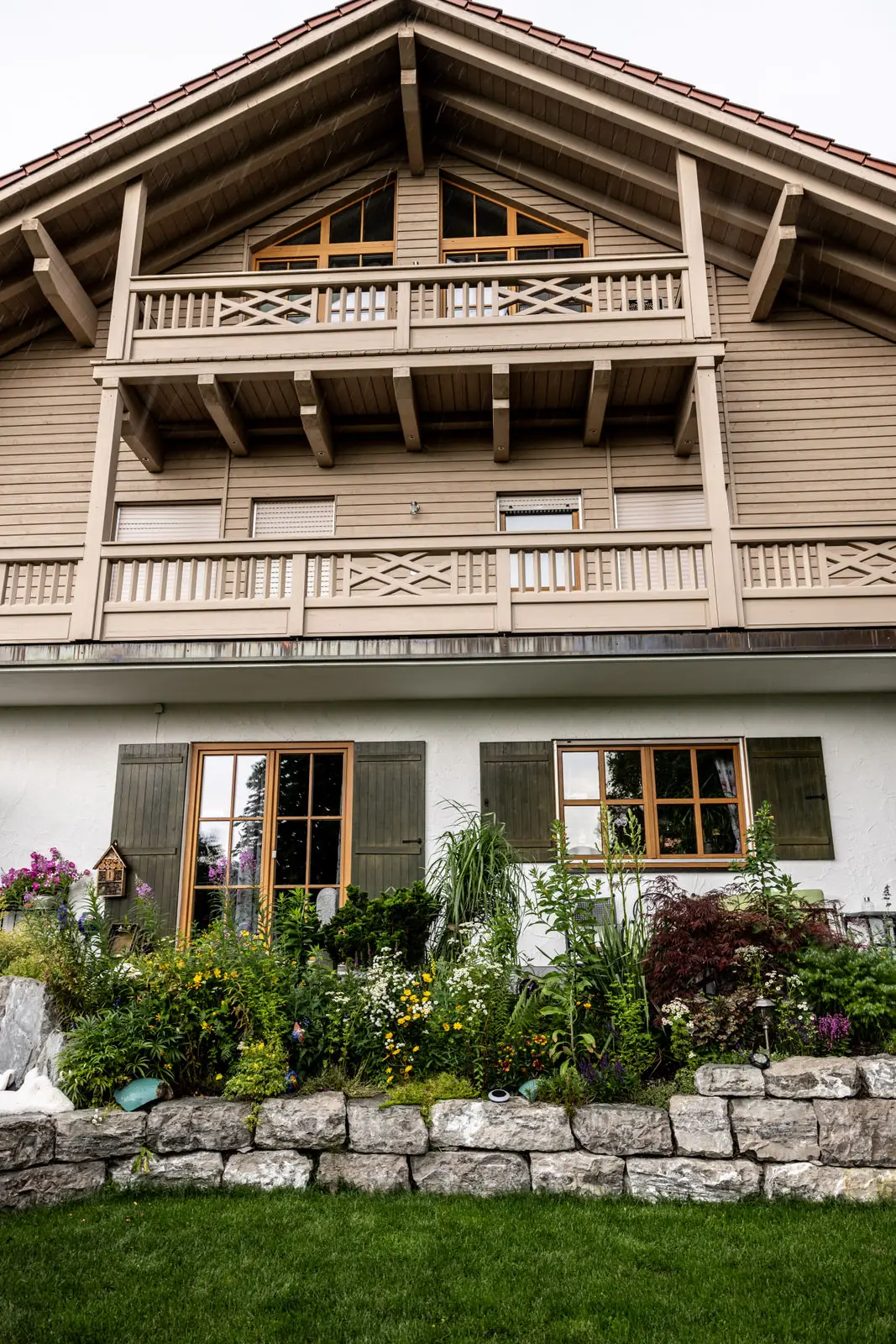 Das Wohnhaus mit Holzbalkonen über dem neu gefassten Beet