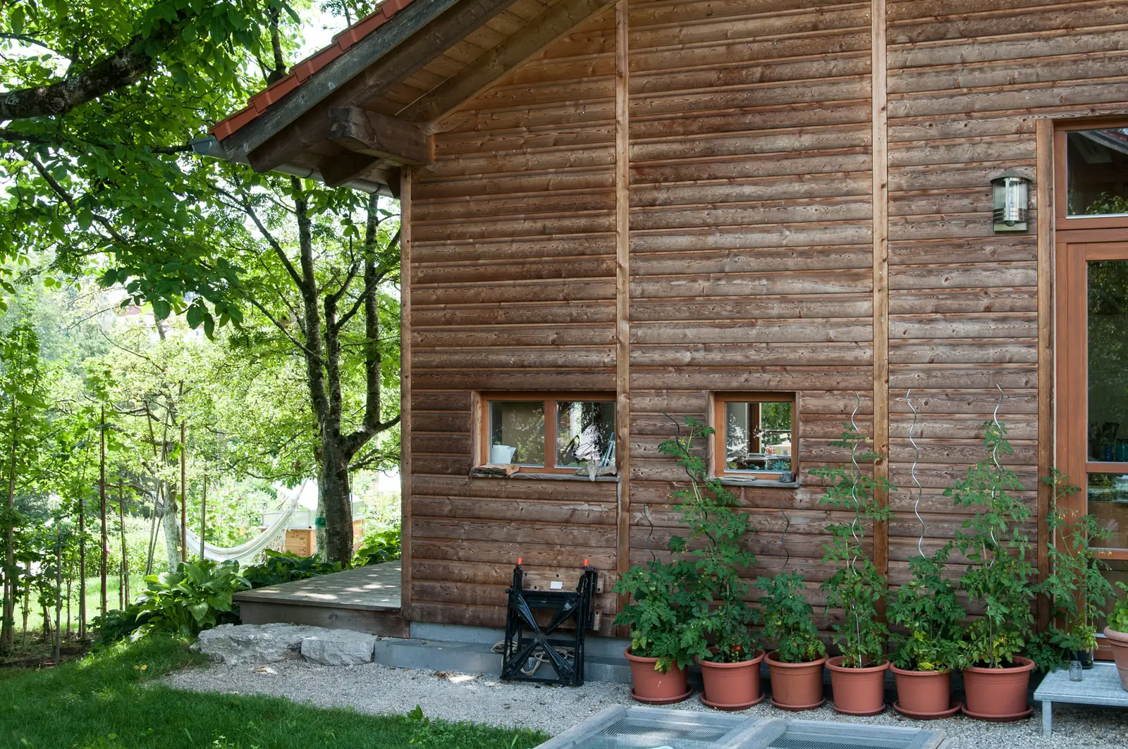 Die Holzfassade mit der Reihe Blumentöpfe entlang der Wand
