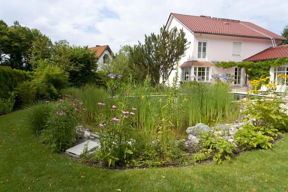Bepflanzter Naturteich mit Gräsern und Stauden im Rasen