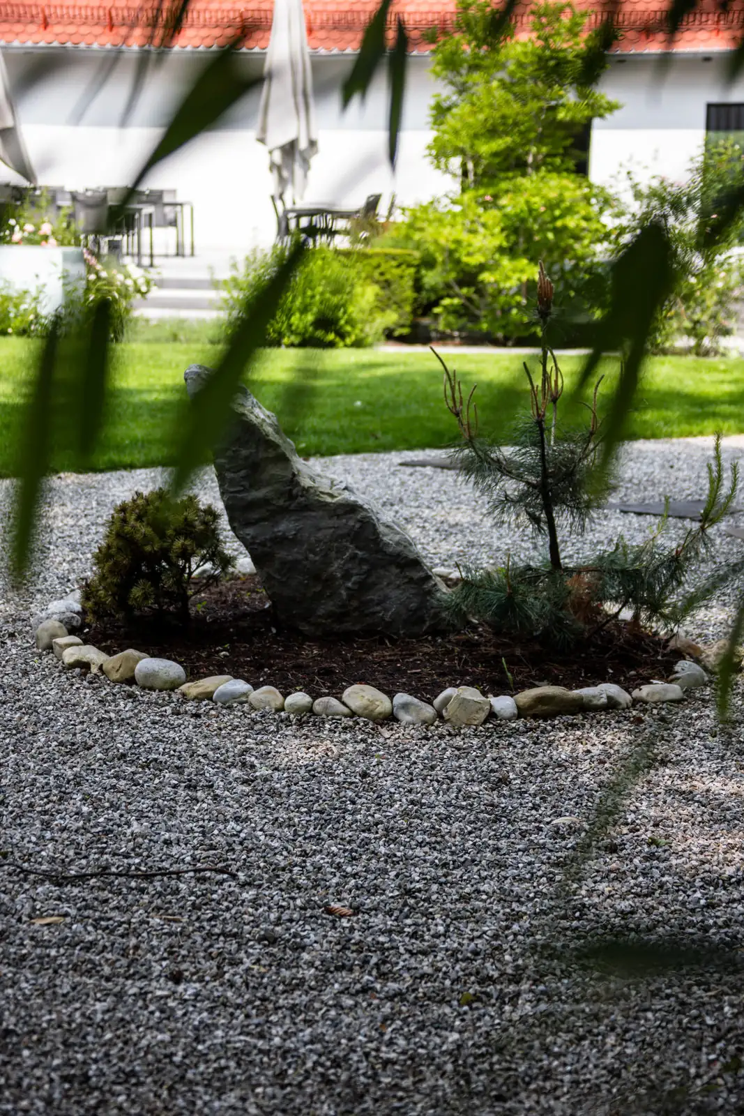 Der Zen-Garten: ein stehender Findling in der Kiesfläche, dazu Kiefer und Formschnitt