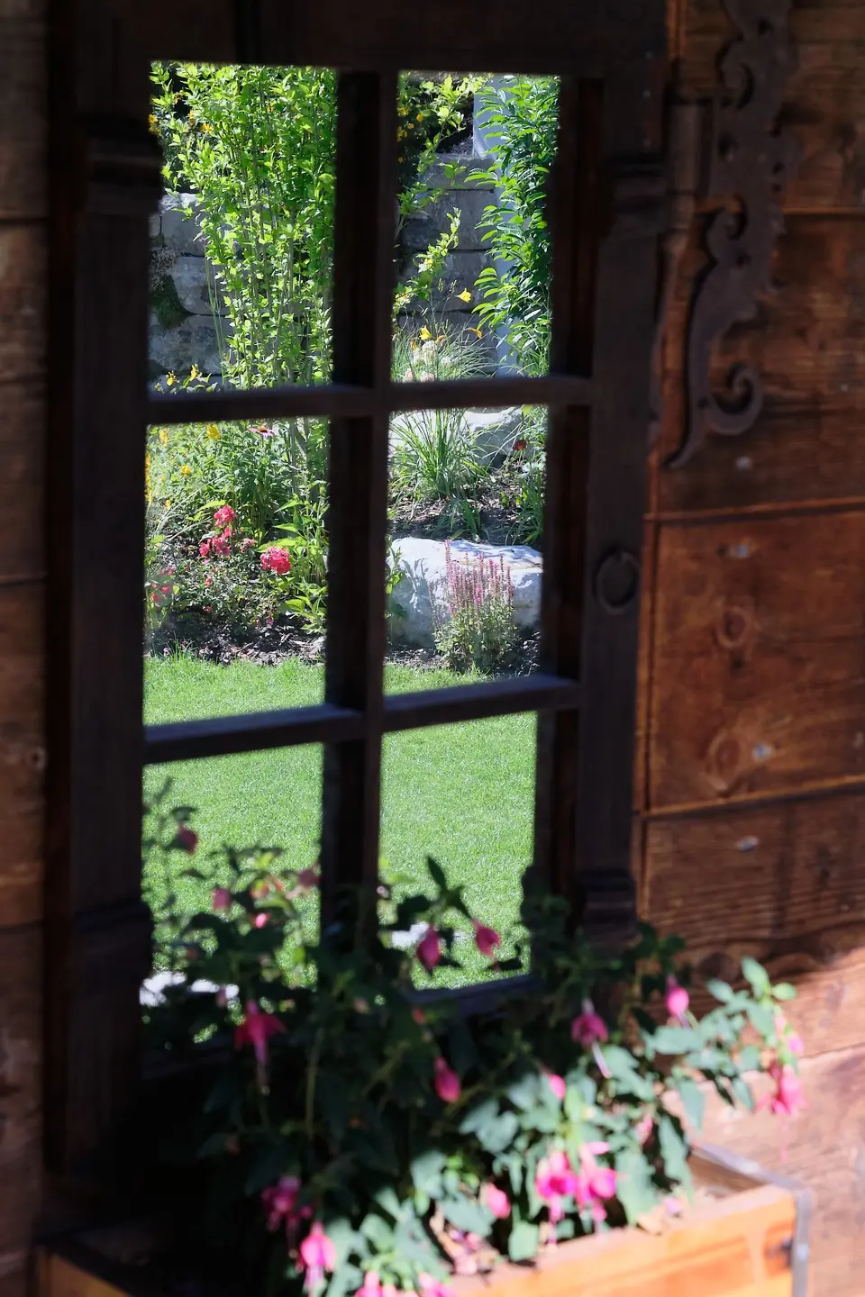 Blick durch ein Sprossenfenster mit Blumenkasten in den Garten