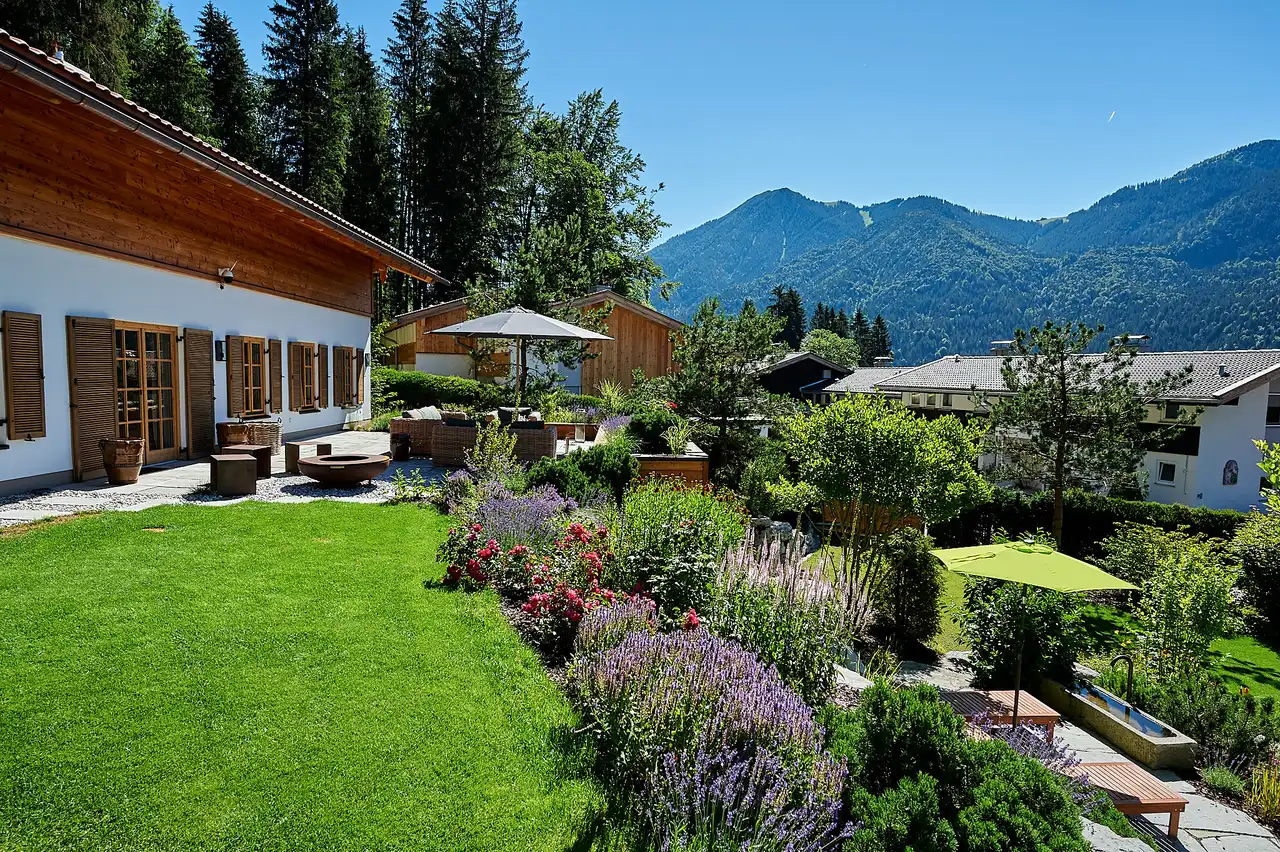 Blick über den Garten mit Sonnenschirm hinaus in die Berge