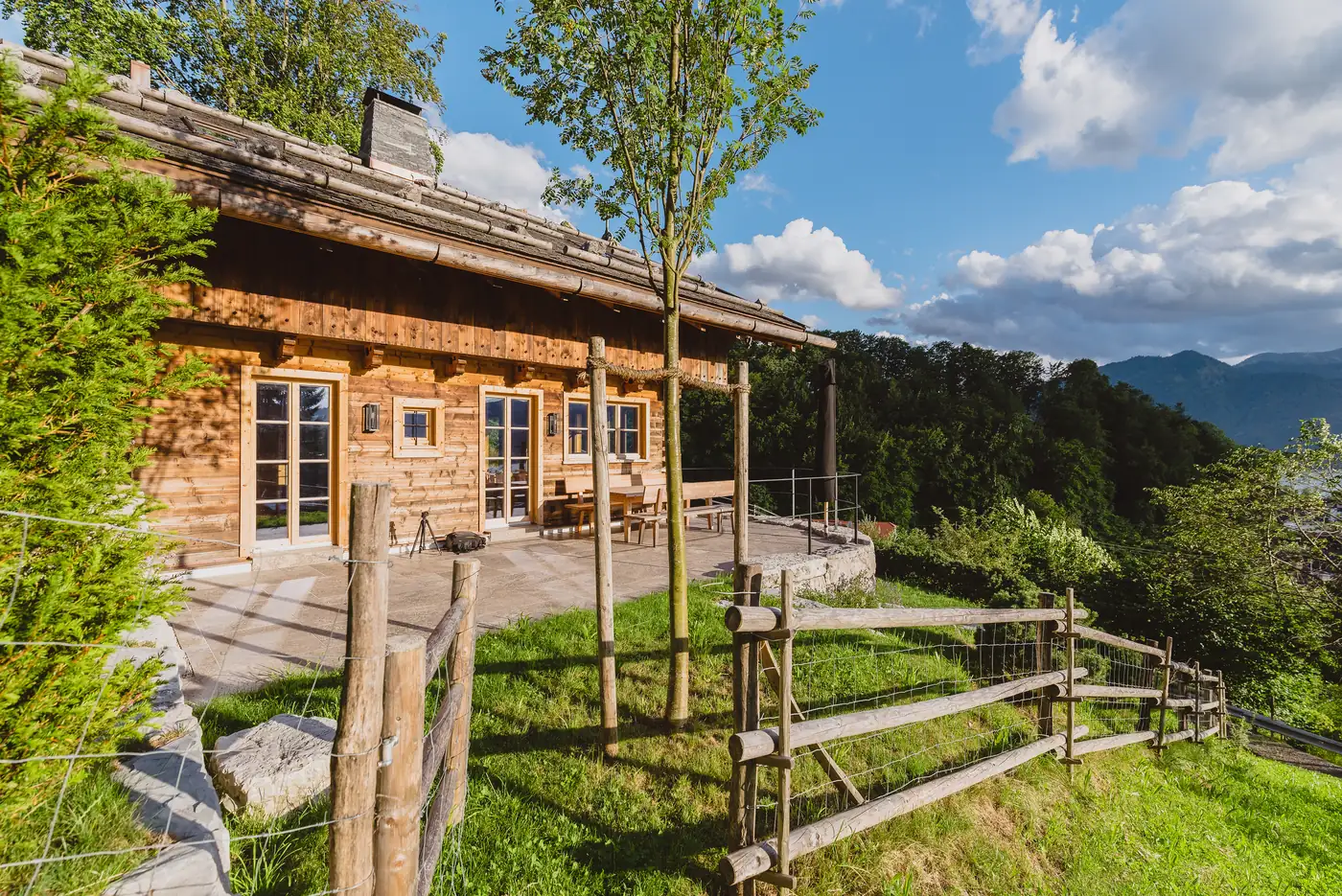 Wie eine Alm: das Haus hinter dem Holzzaun, davor die junge Wiese