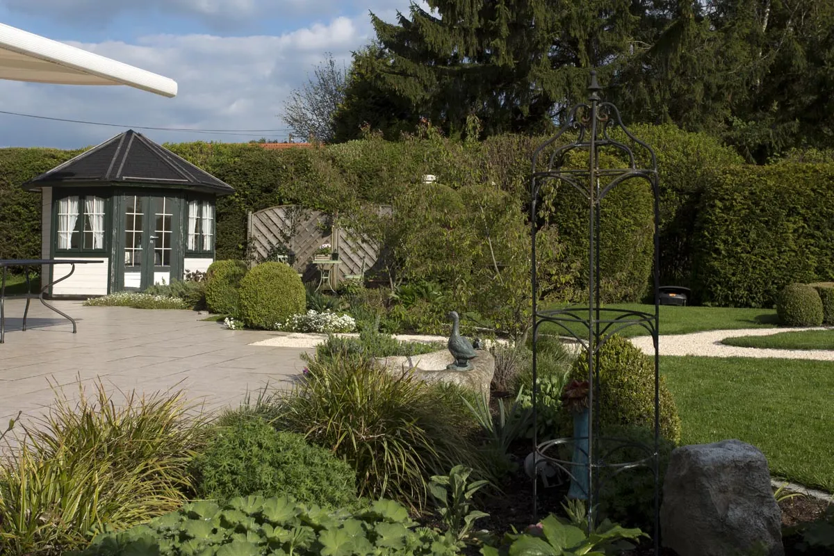 Der Pavillon an der Plattenterrasse, gerahmt von hohen Hecken