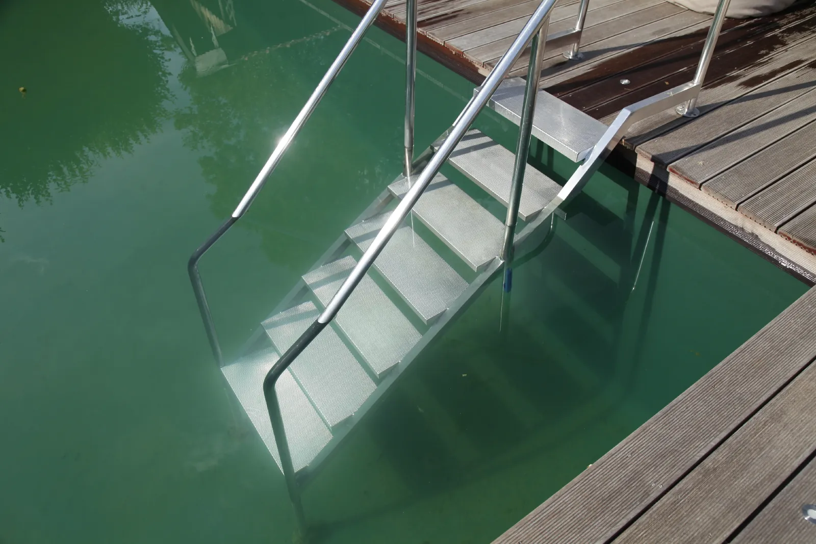 Die Edelstahlleiter im klaren, grünen Wasser