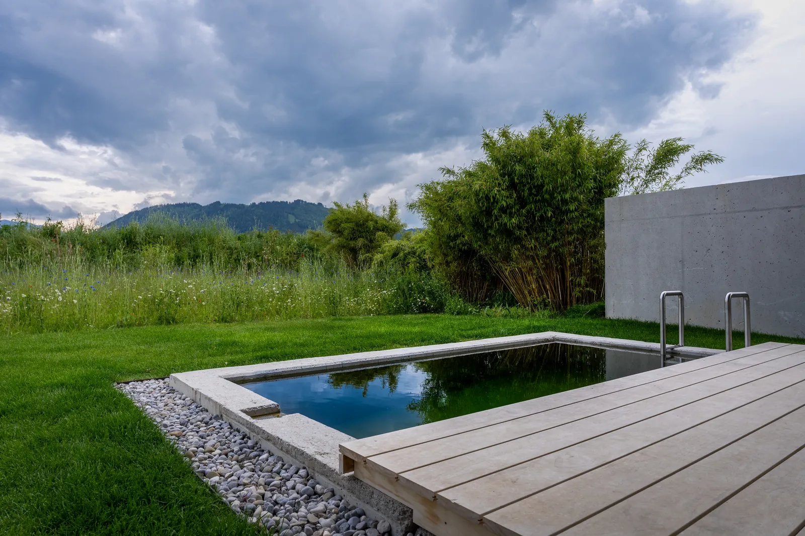 Das schmale Becken einer Lodge zwischen Holzdeck und Gräsern