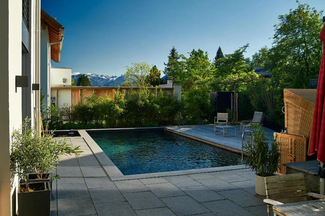 Der Pool liegt eingelassen in der Terrasse, dahinter die Berge