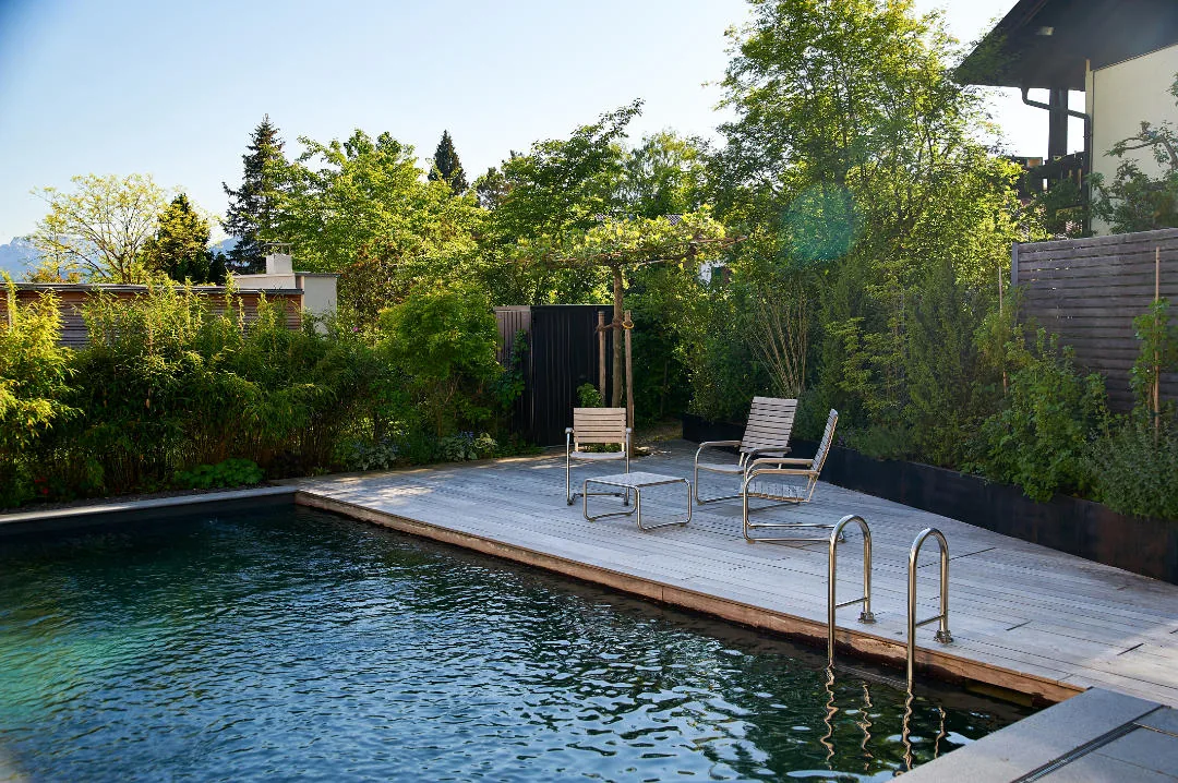 Am Tag: der Pool mit Holzdeck und Einstieg im grünen Gartenzimmer