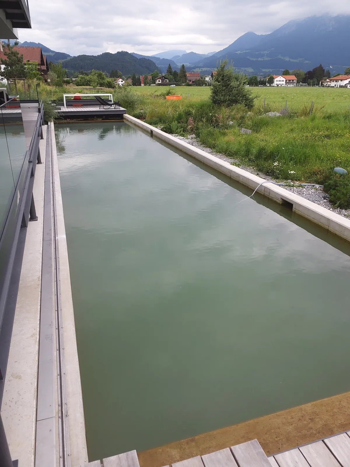 Der Beckenrand aus Sichtbeton, dahinter offenes Land