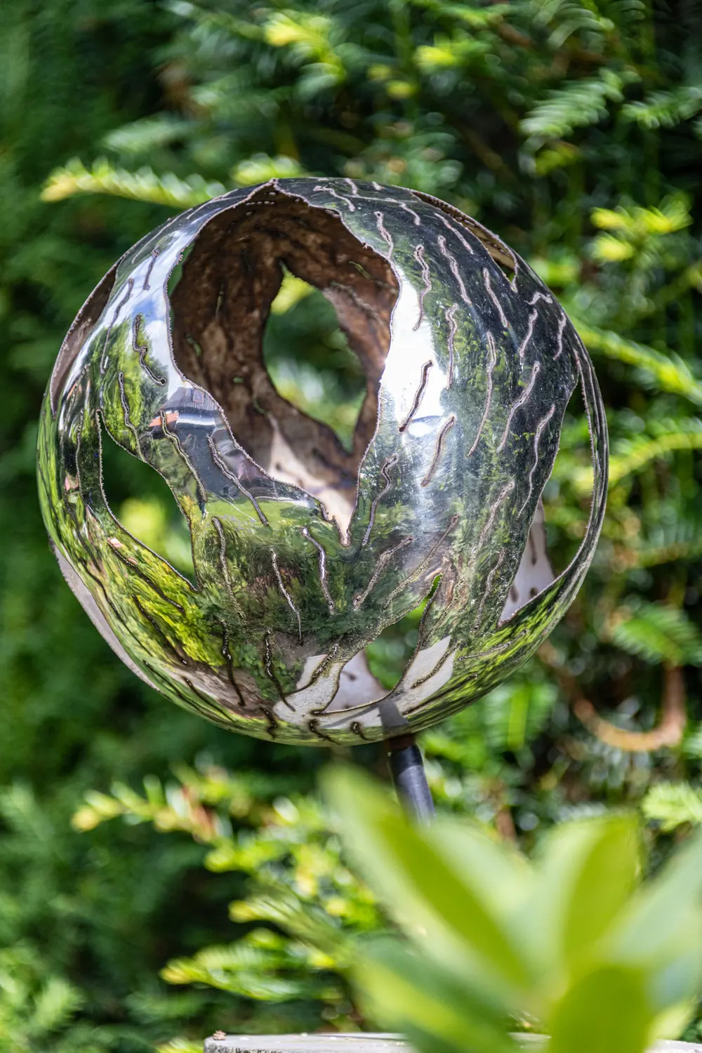 Eine Edelstahl-Kugel als Gartenkunst im Beet
