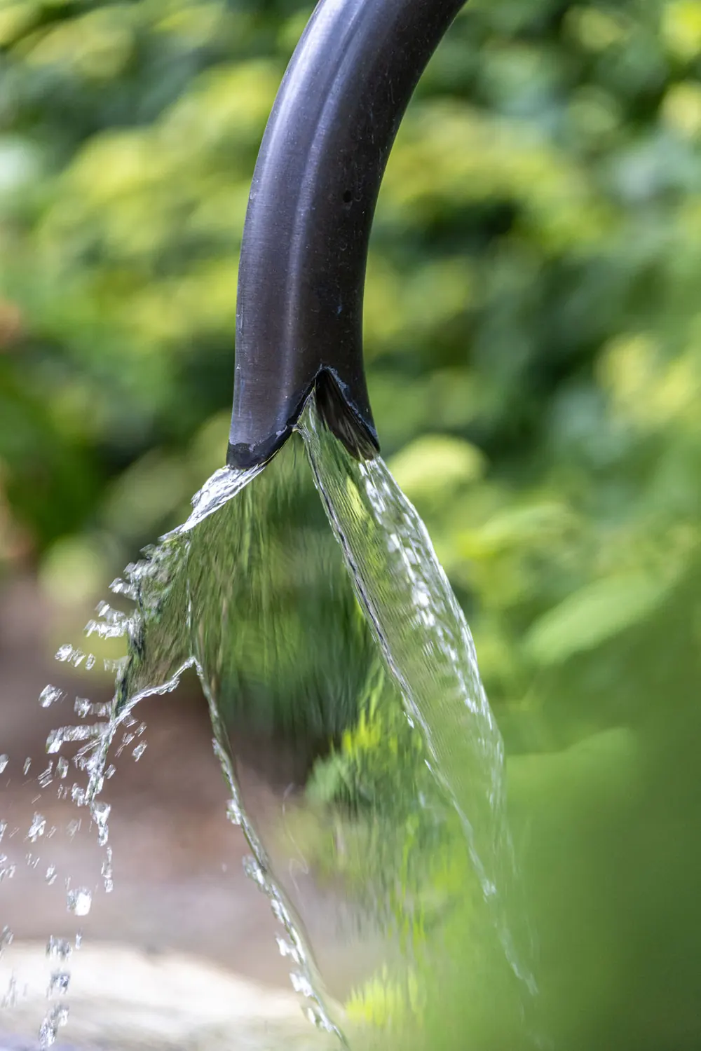 Wasser läuft aus dem Auslass in den Natursteintrog