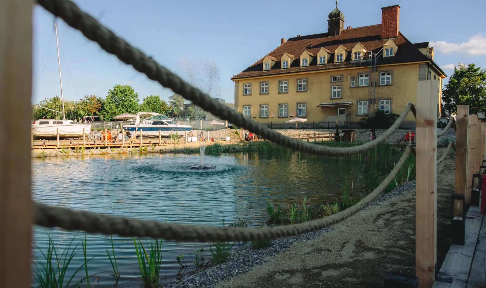 Blick über das Wasser zum historischen Gebäude, gerahmt von einem Schiffstau