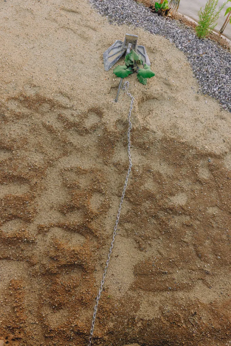 Ein Anker liegt im Sand am Ufer
