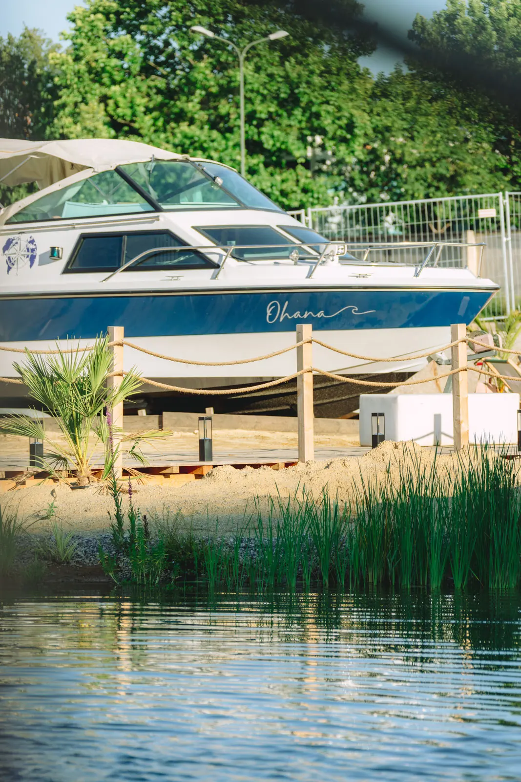 Gräser im Flachwasser vor einem Motorboot am Sandstrand