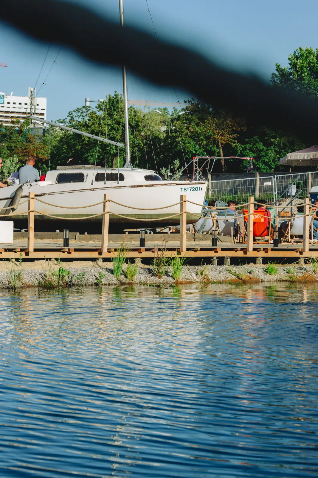 Ein Segelboot liegt am Ufer des Schwimmteichs an