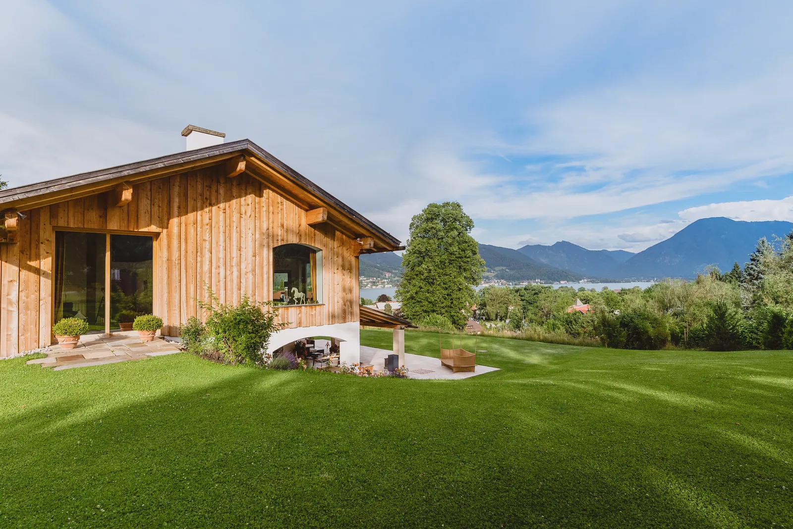 Das Holzhaus über dem Rasen, dahinter die Berge