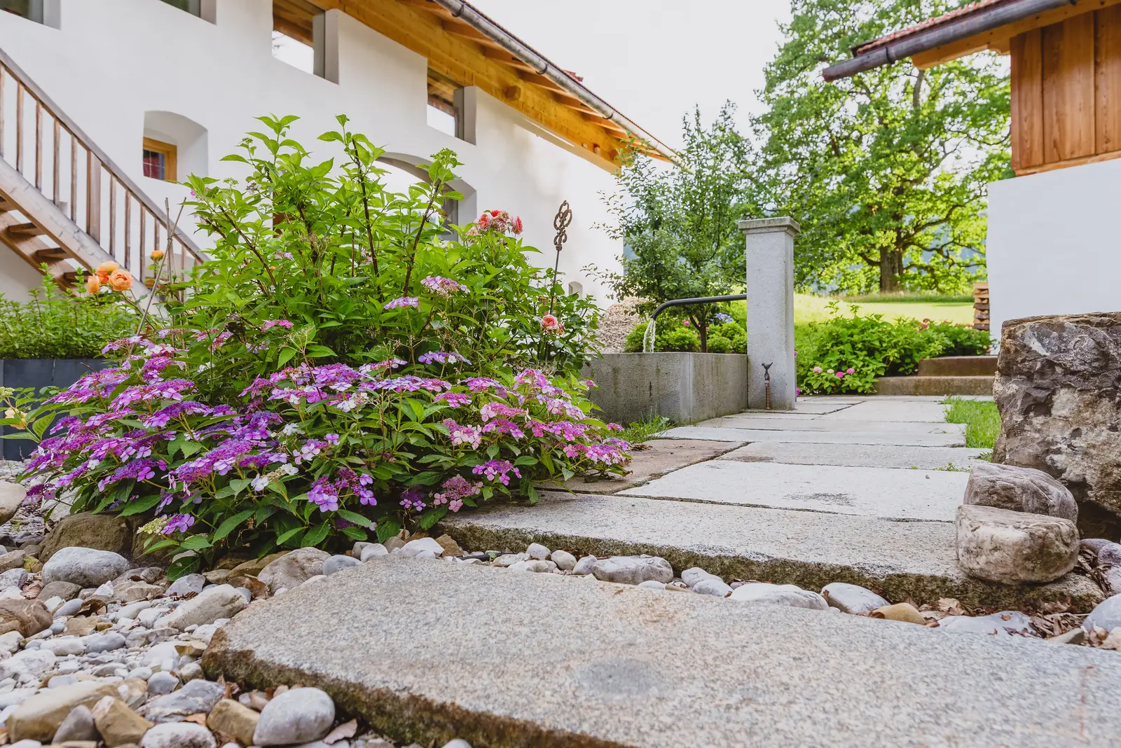Blühende Stauden an den Trittplatten, rechts das Brunnenbecken