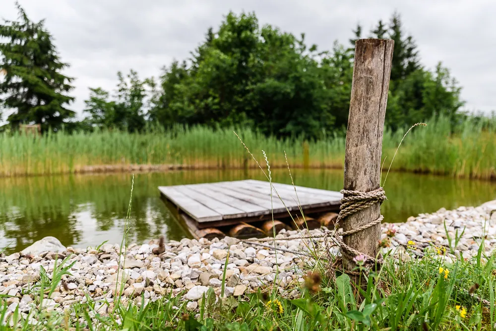 Ein kleiner Holzsteg am Kiesufer, daneben ein alter Pfosten