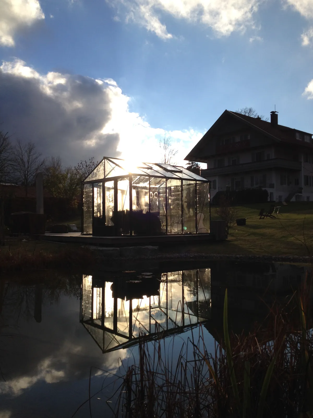 Abendlicht: das Glashaus spiegelt sich im Wasser