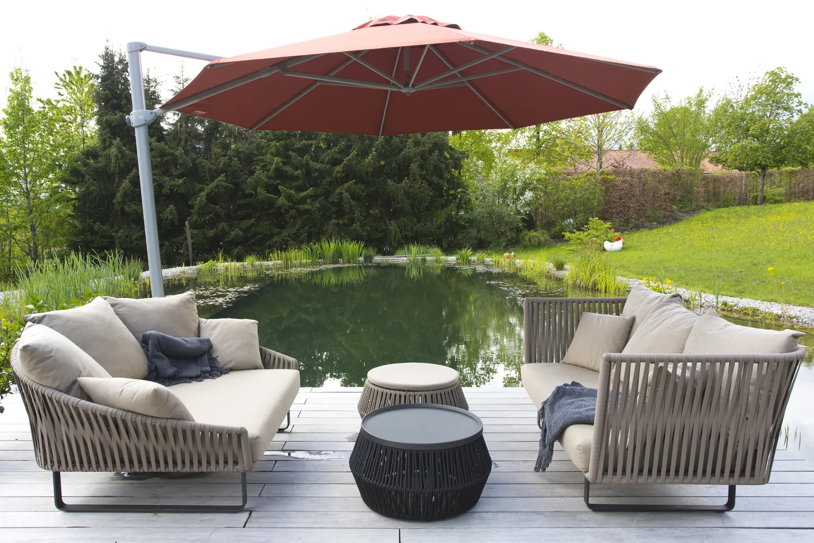 Der Sitzplatz am Wasser mit Sonnenschirm und Lounge