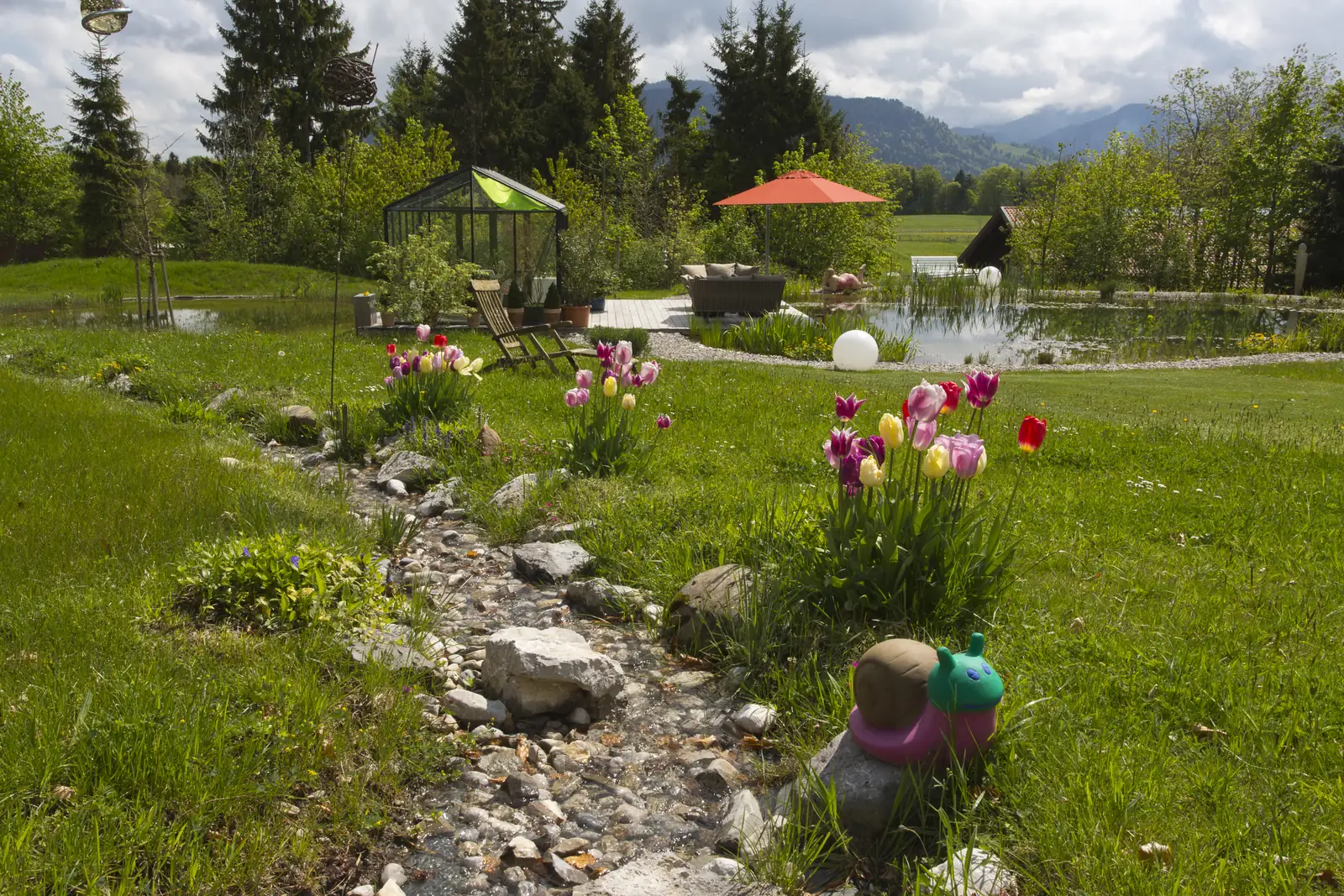 Der Bachlauf schlängelt sich durch den Rasen, Tulpen am Ufer