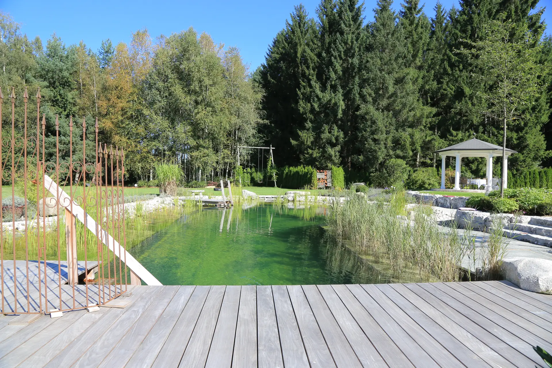 Vom Holzdeck über das grüne Wasser: der Blick zum Garten