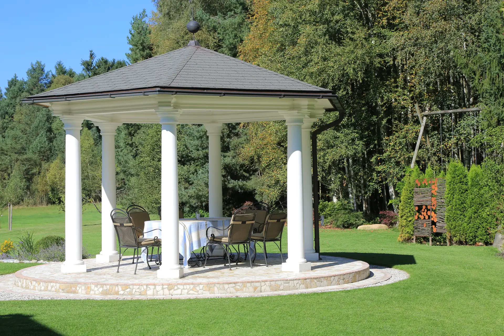Der Pavillon mit gedecktem Tisch am Rand der großen Wiese