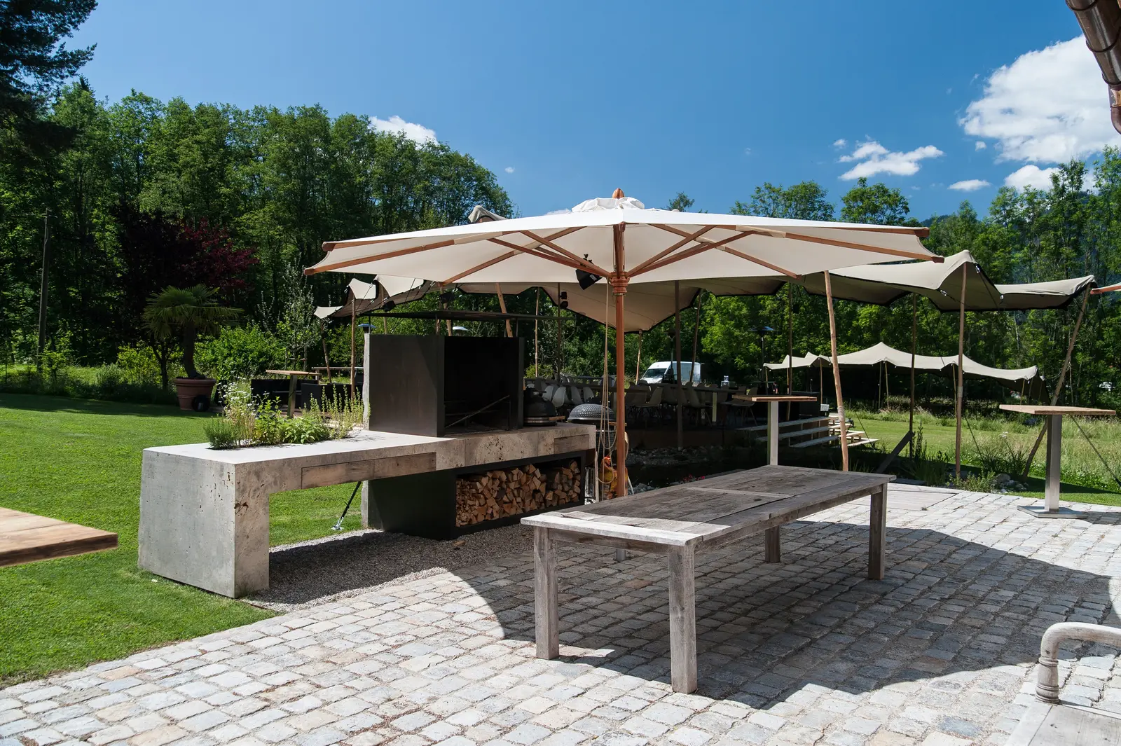 Die Terrasse mit langem Tisch unter den Schirmen