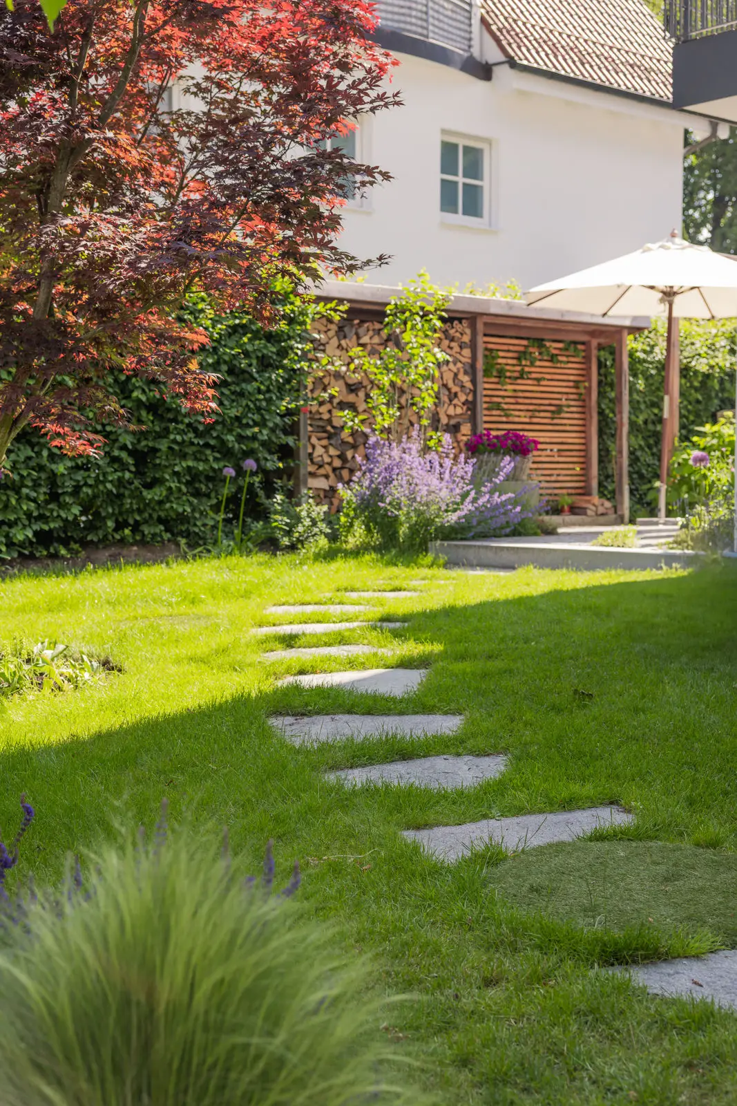 Trittplatten führen über den Rasen zur Pergola