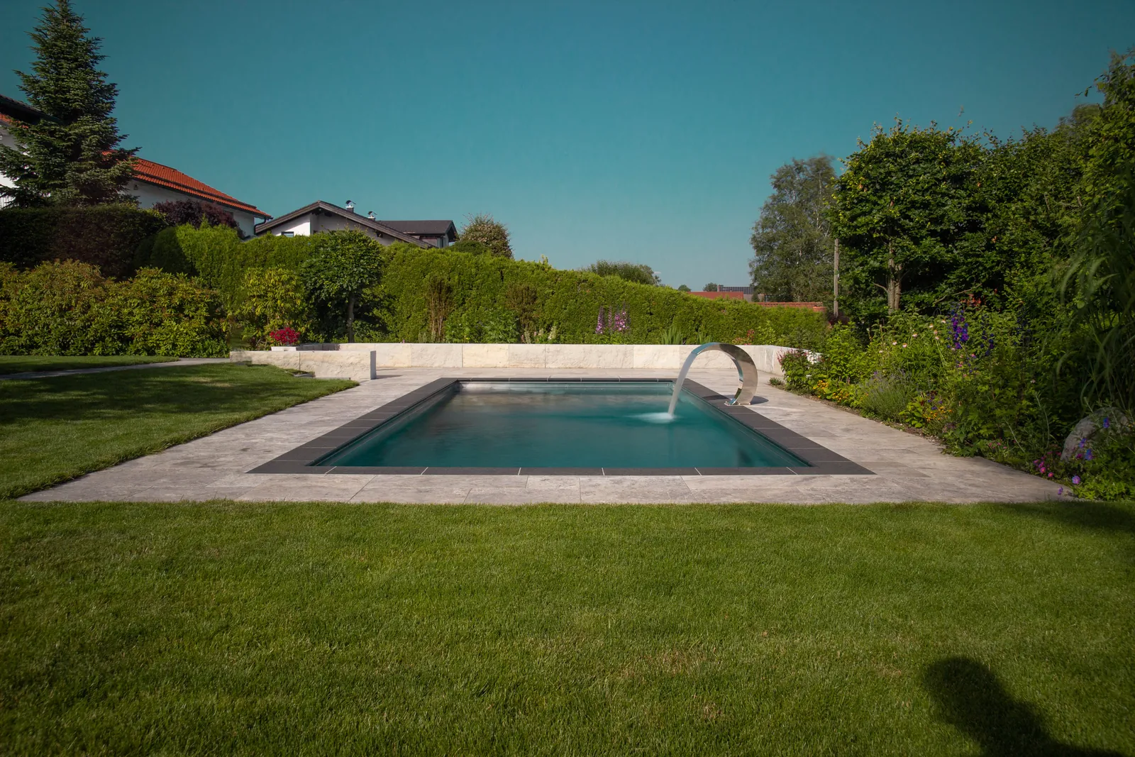 Die lange Wasserfläche vor der Hecke