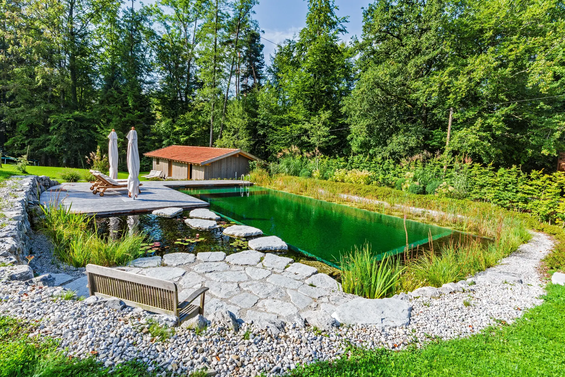 Bank am Natursteinufer, dahinter der Pavillon