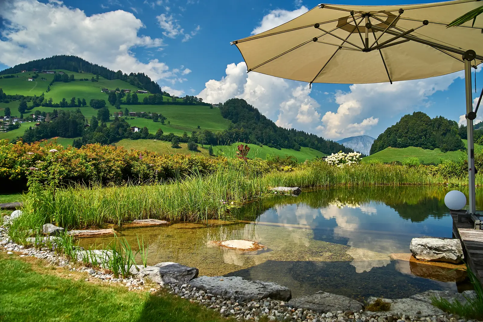 Sonnenschirm am Ufer, dahinter die Tiroler Berge