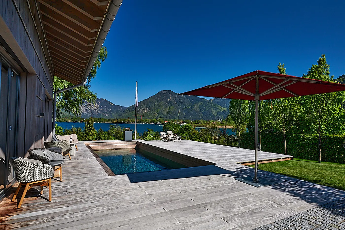Das Holzdeck am Pool mit Blick auf See und Berge