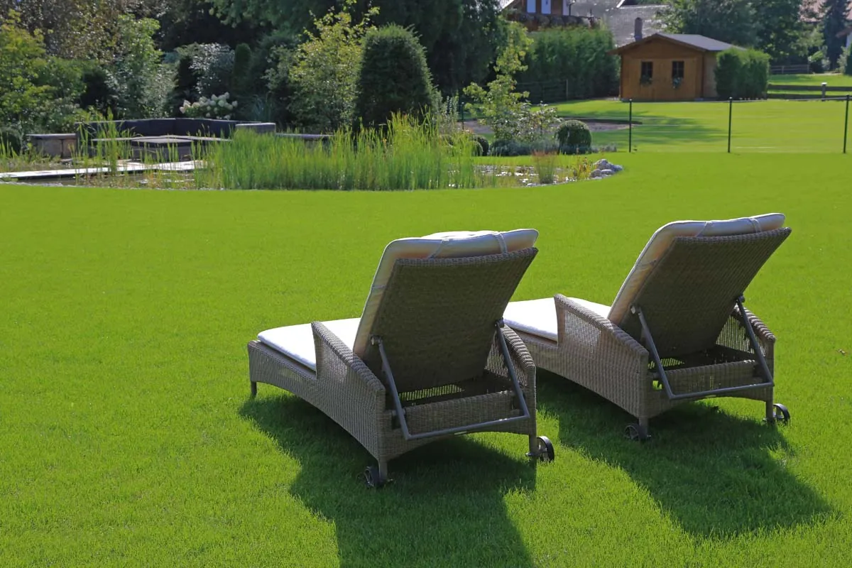 Zwei Liegen auf dem Rasen, hinten das Gartenhaus am Teich