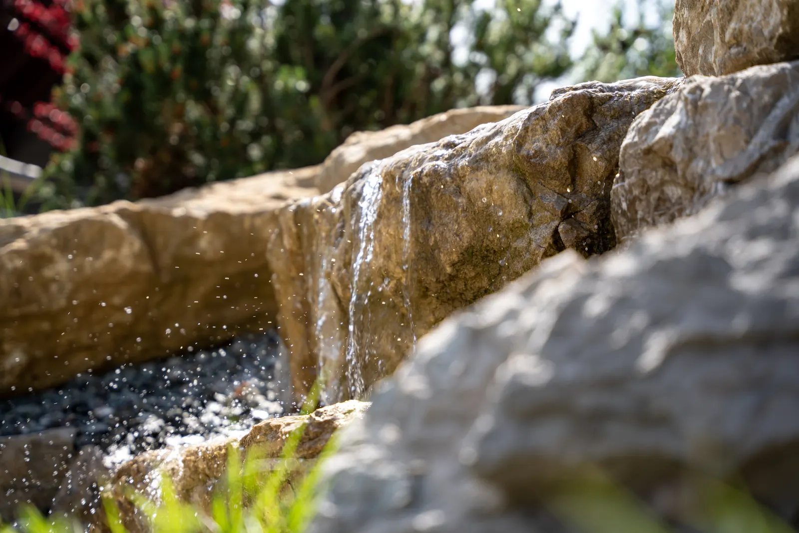 Wasser läuft über die Felskante – der Bachlauf speist den Teich