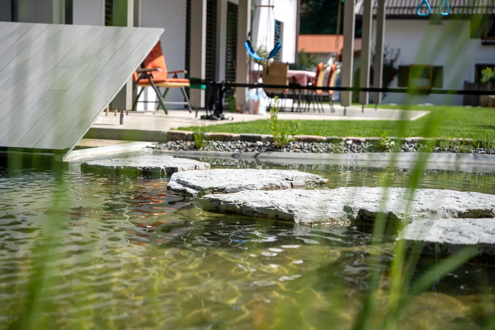 Der Steg am Ufer, dahinter Liegen und Sonnenschirm