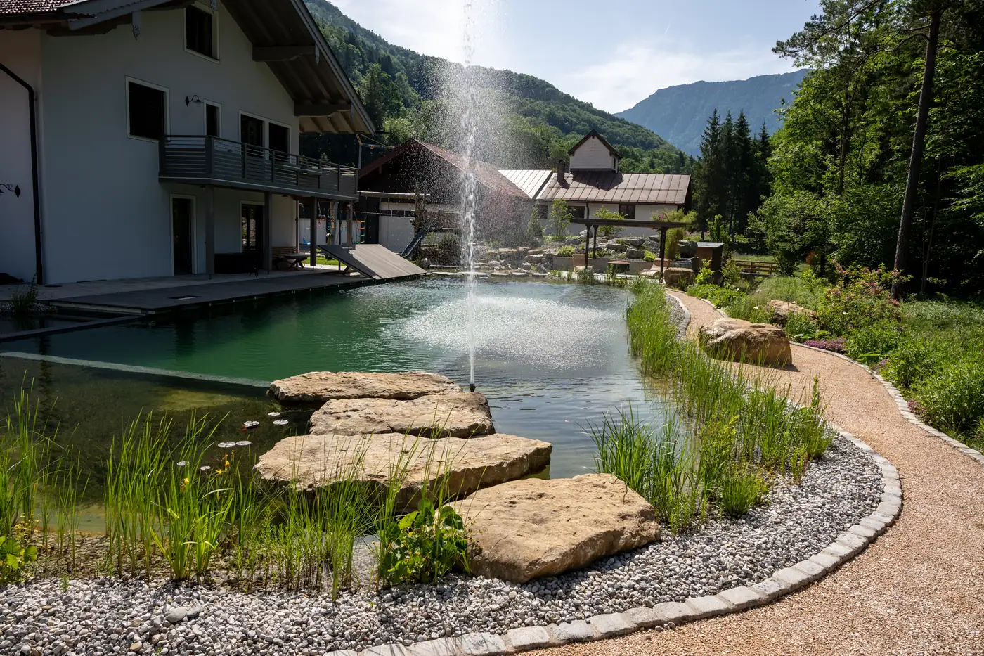 Wasserfläche mit Fontäne, dahinter das Haus am Hang