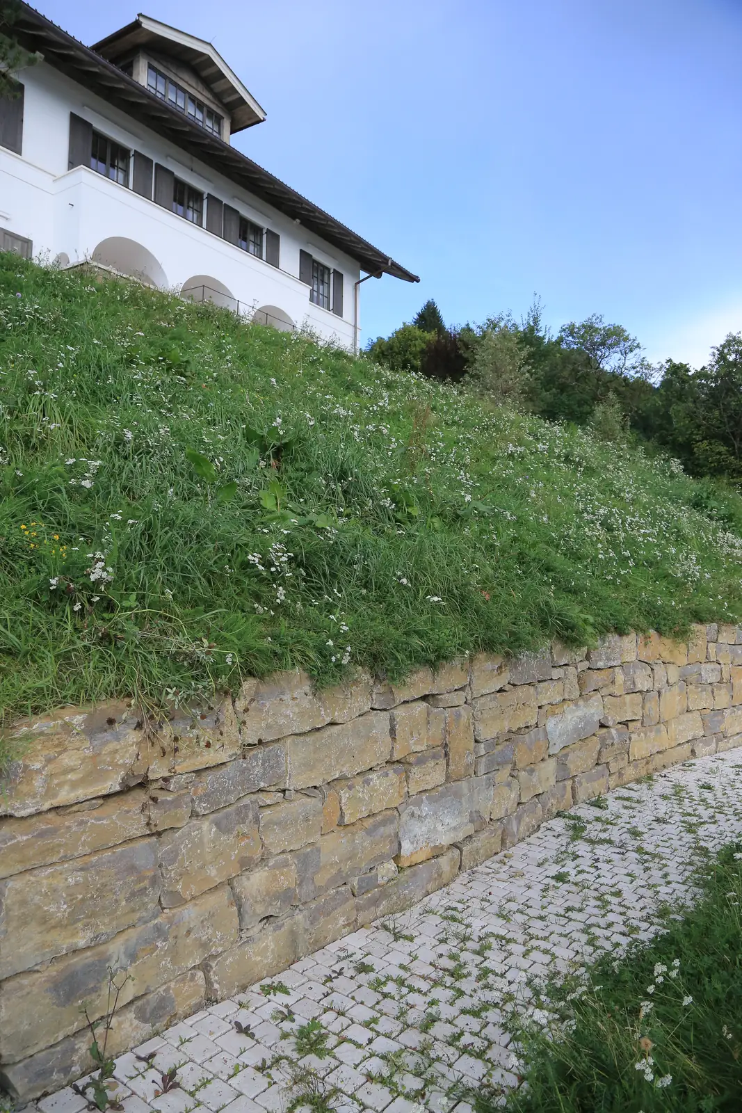 Die Natursteinmauer begleitet den Weg aus Kleinpflaster