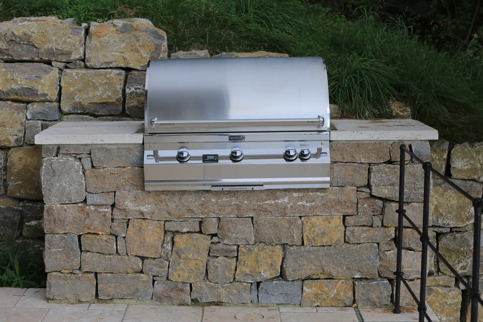 Der Grill sitzt eingebaut in der Bruchsteinmauer